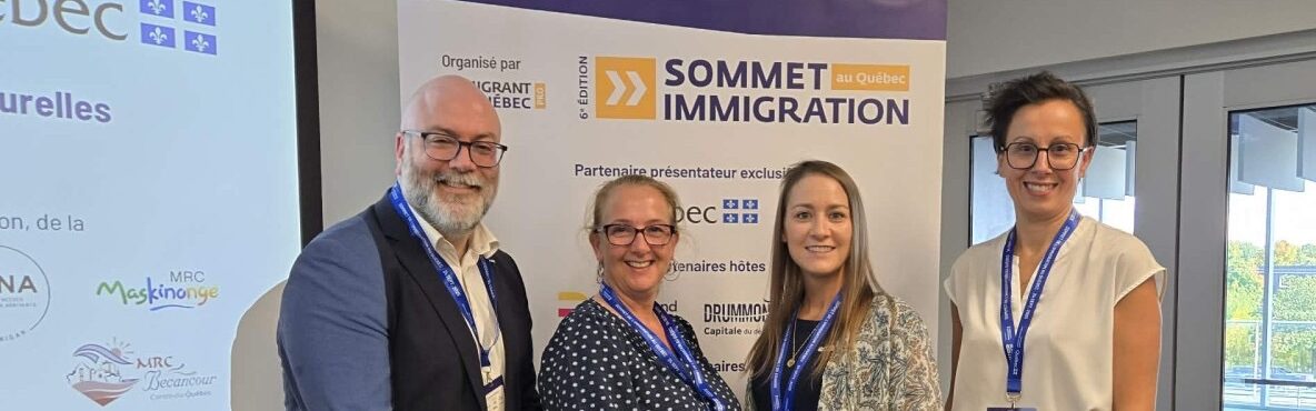 Quatre panélistes réunis lors du Sommet de l’Immigration de Drummondville, représentant la MRC de Bécancour et d’autres partenaires régionaux, posant devant la bannière officielle de l’événement organisé par le MIFI.
